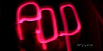 Lightpainting photo by Poppy Veale writing the word 'POP' in black background by some stairs.