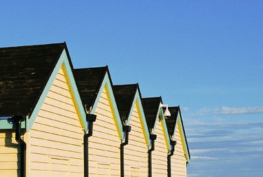 Diagonal view of five Brighton huts in a bright blue sky background.  Photo by Eva Kalpadaki.