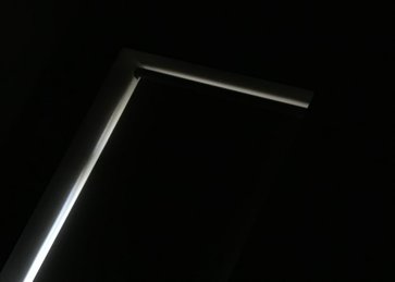 Ασπόμαυρη εικόνα όπου μόνο το φως που περνάει απο τις άκρες της κουρτίνας ενός παραθύρου φαίνεται να γράφει το σχήμα Γ.